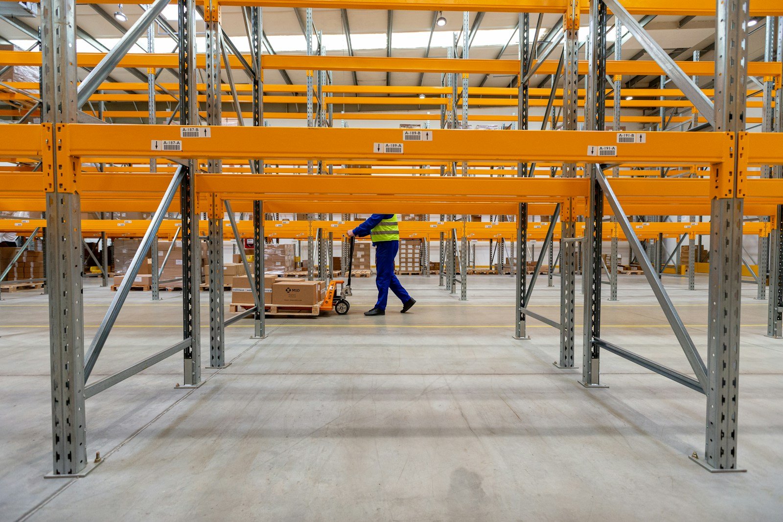 Warehouse operator moving a pallet through an organised storage facility